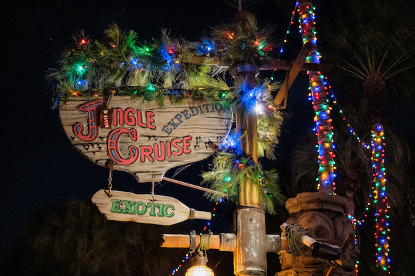 The sign for Jingle Cruise at Magic Kingdom surrounded by garland and Christmas lights.