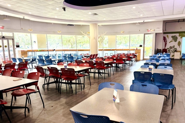 A large restaurant dining space with square tables and red and blue chairs.