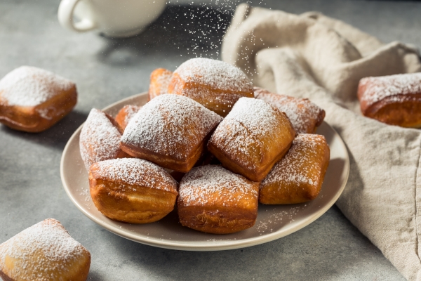 A plate of fresh beignets topped with powdered sugar.