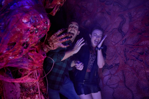 A man and woman scream as a scare actor jumps out at them at HHN in 2026.
