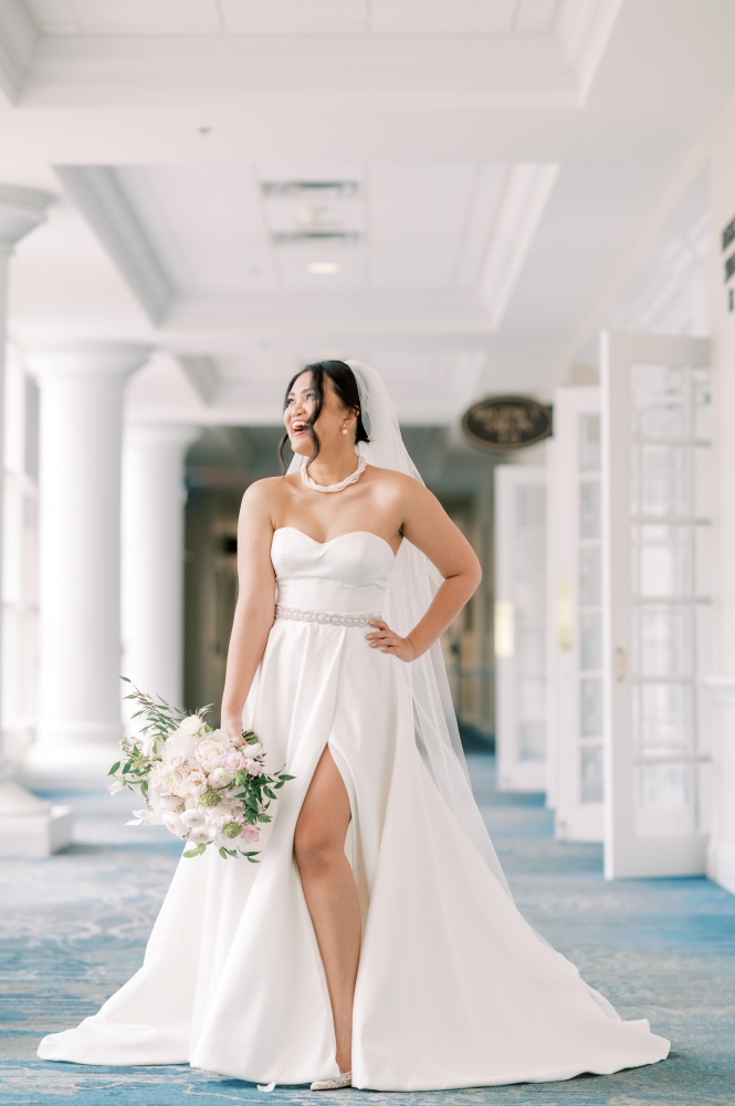 A bride stands in a bright hallway with white columns and French doors at Rosen Plaza.