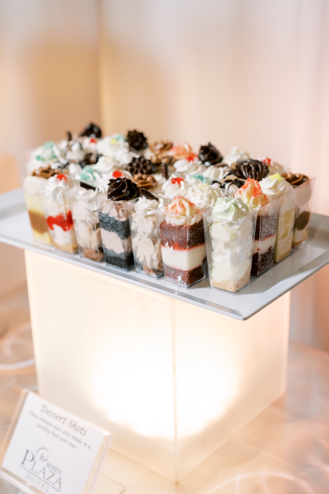 A display of desserts in shot glasses and a sign from Rosen Plaza catering. 