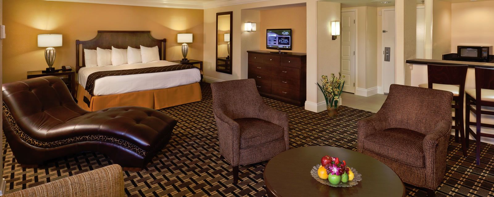 Junior Suites with bed, chairs, tvs, and table with fruit
