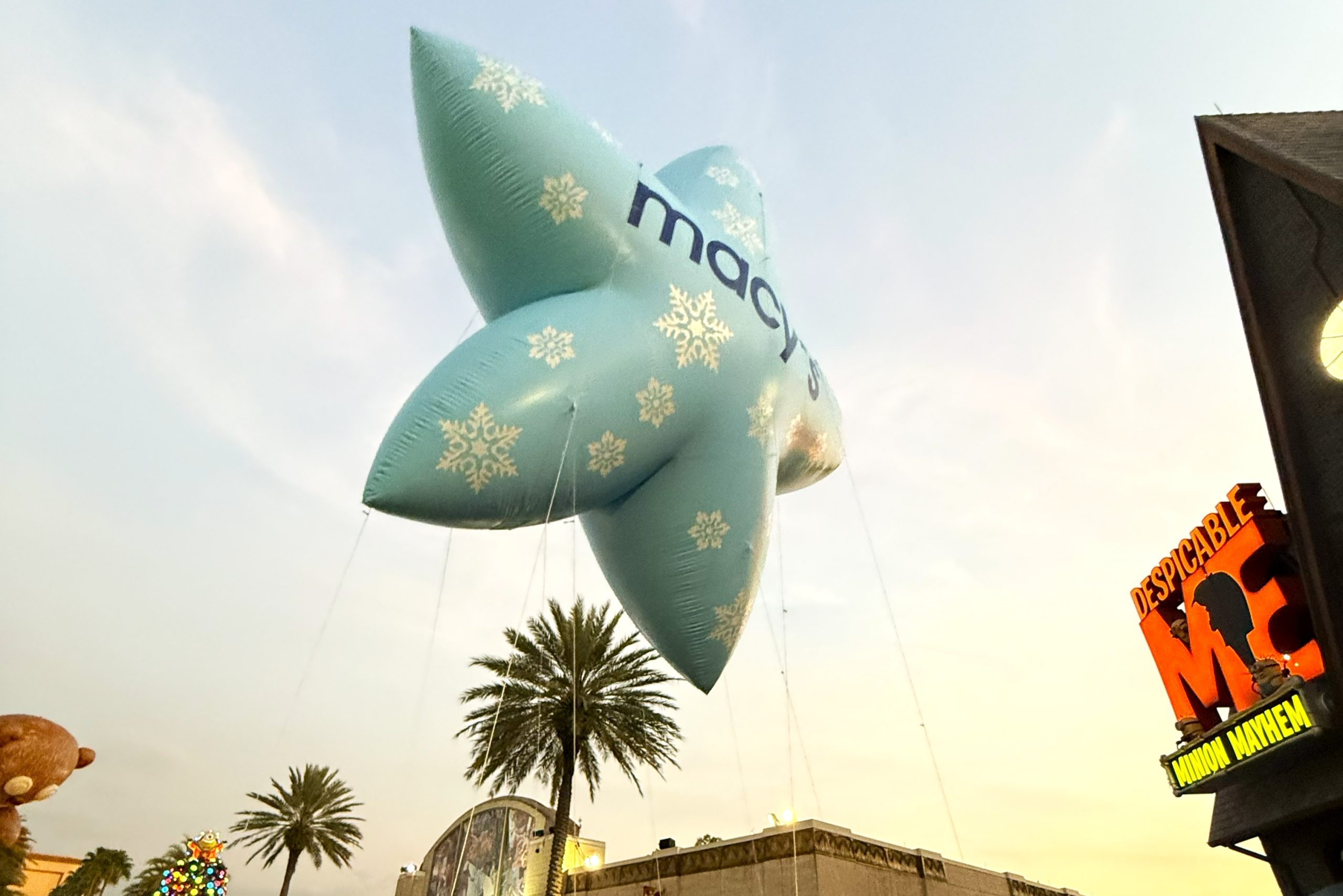 A light blue star-shaped parade balloon with snowflakes glides through a sunset sky at Universal Studios Florida on Thanksgiving.
