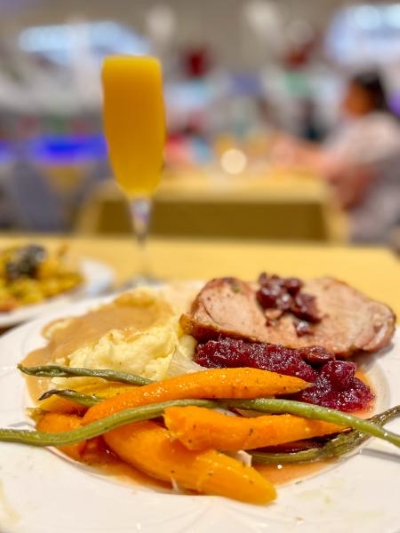 A plate with carrots, sliced turkey, mashed potatoes, and a Champagne flute with a mimosa. 
