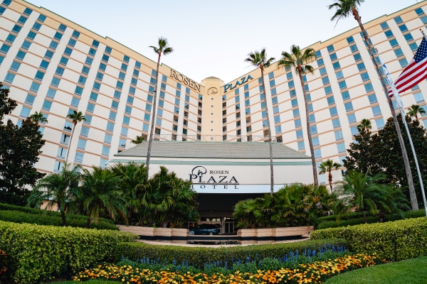 Flowers blooming and palm trees swaying in front of the entrance to Rosen Plaza Hotel on International Drive in Orlando.