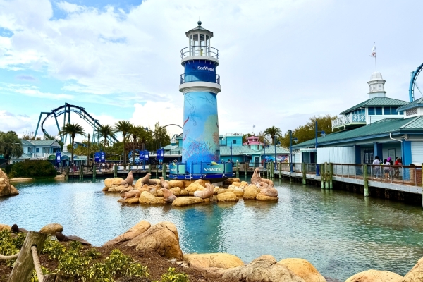 The light house at the entrance to SeaWorld Orlando surrounded by a small pond and walrus statues.