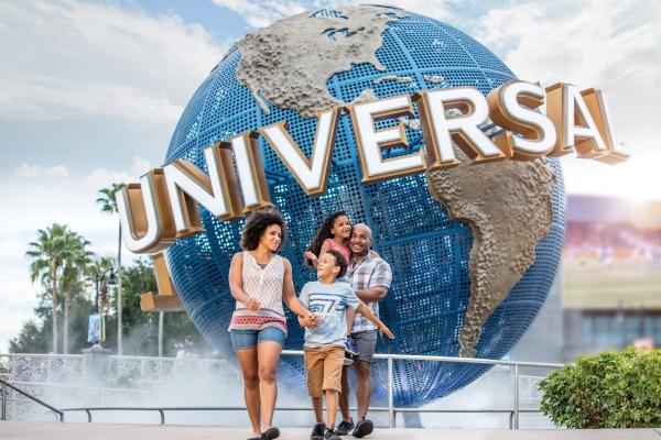 A family walking in front of the entrance to Universal Orlando Resort, with complimentary transportation provided by Rosen Plaza Hotel in Orlando.