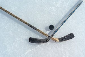 Two hockey sticks and a puck on ice
