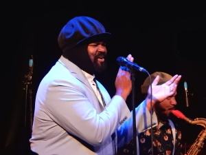 Jazz musician Gregory Porter singing and clapping into a microphone.